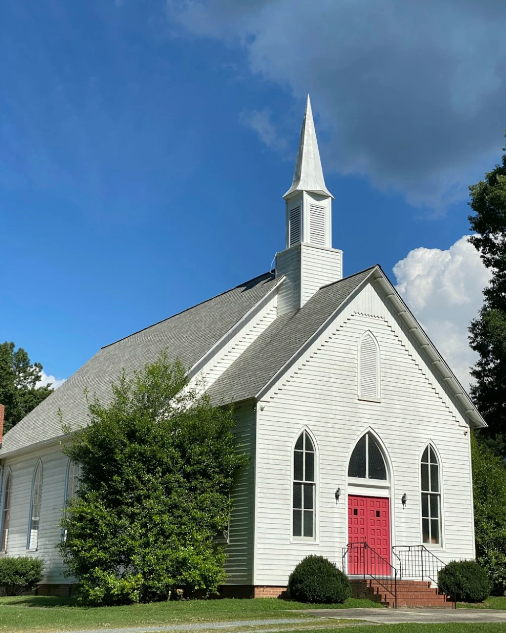White wooden church with red doors and steeple