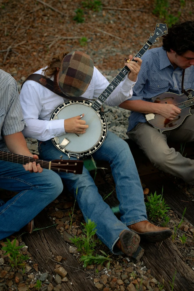 Three musicians playing banjo and mandolin outdoors